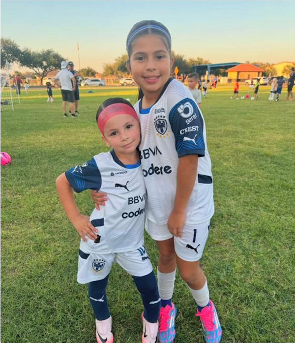 Dos niñas con los jerseys de Rayados en la cancha